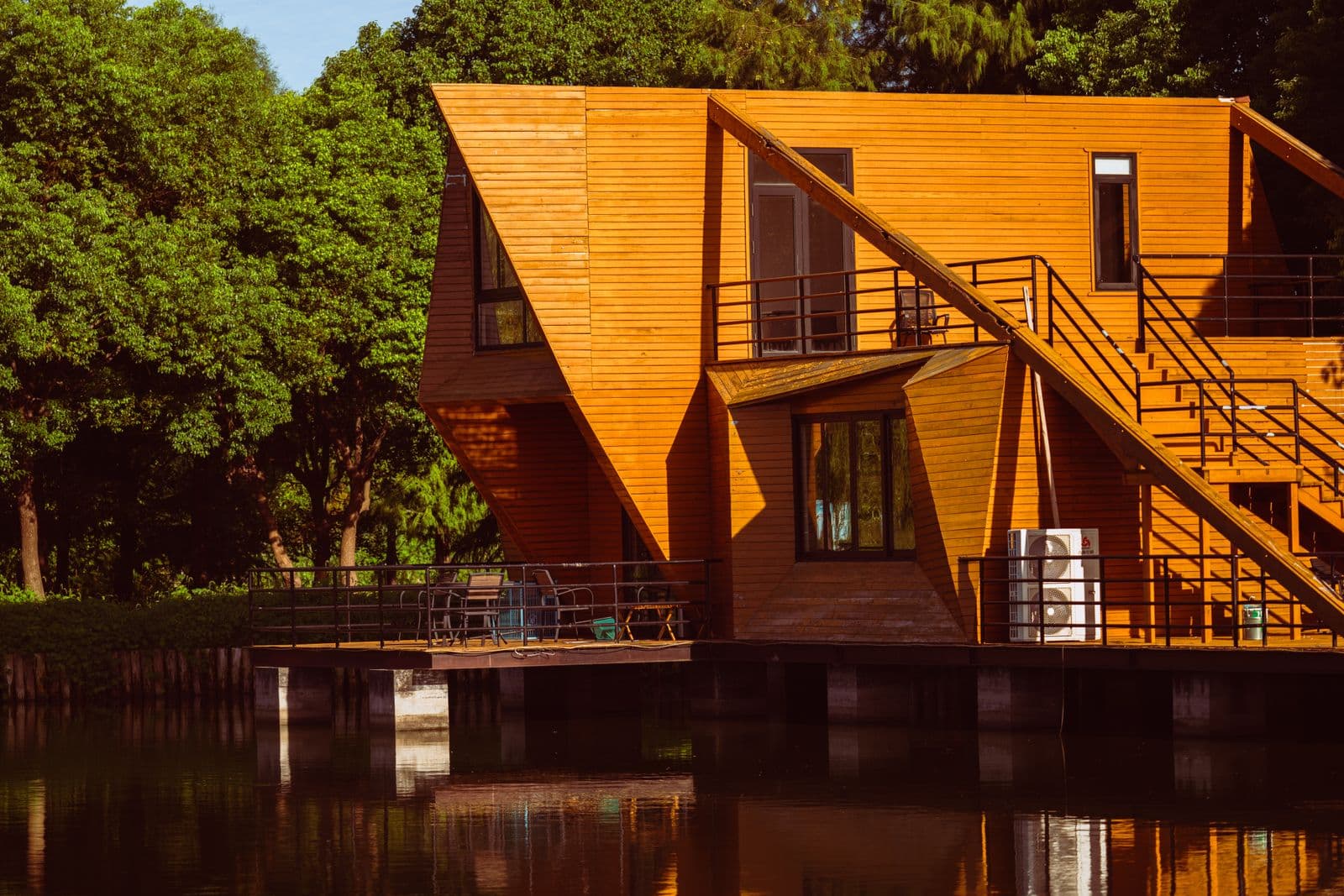 Beautiful modern wooden house by a tranquil lake surrounded by lush greenery.