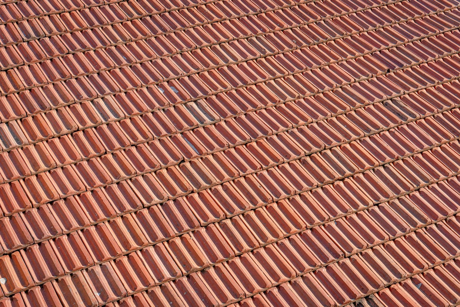 Aerial view of a textured red clay tile roof with a repeating pattern.