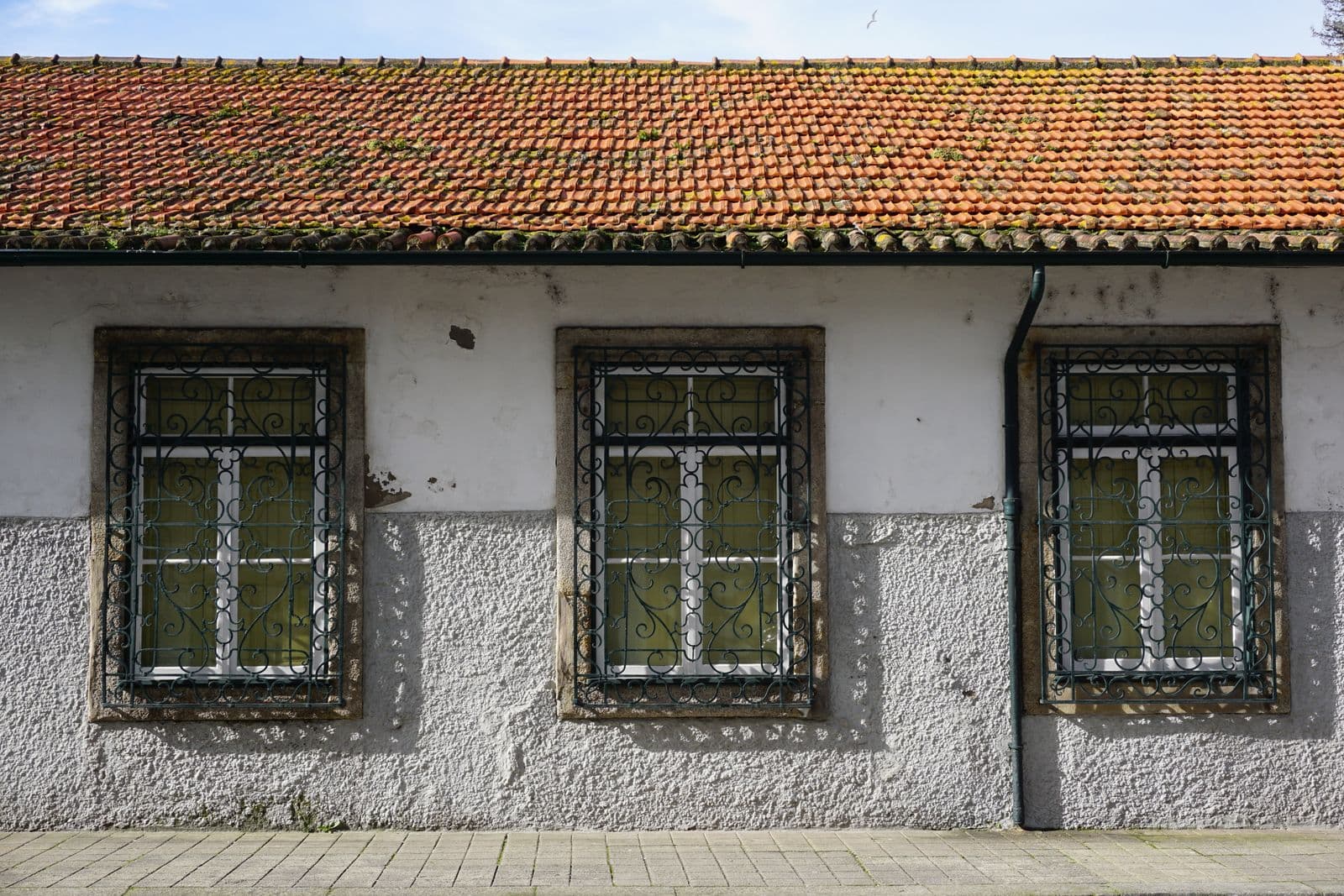 An architectural detail of a traditional building in Porto, Portugal, featuring a tiled roof and decorative windows.