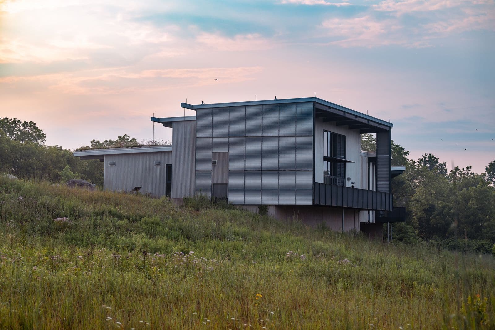 A contemporary home nestled in a peaceful grassland setting during a serene evening.