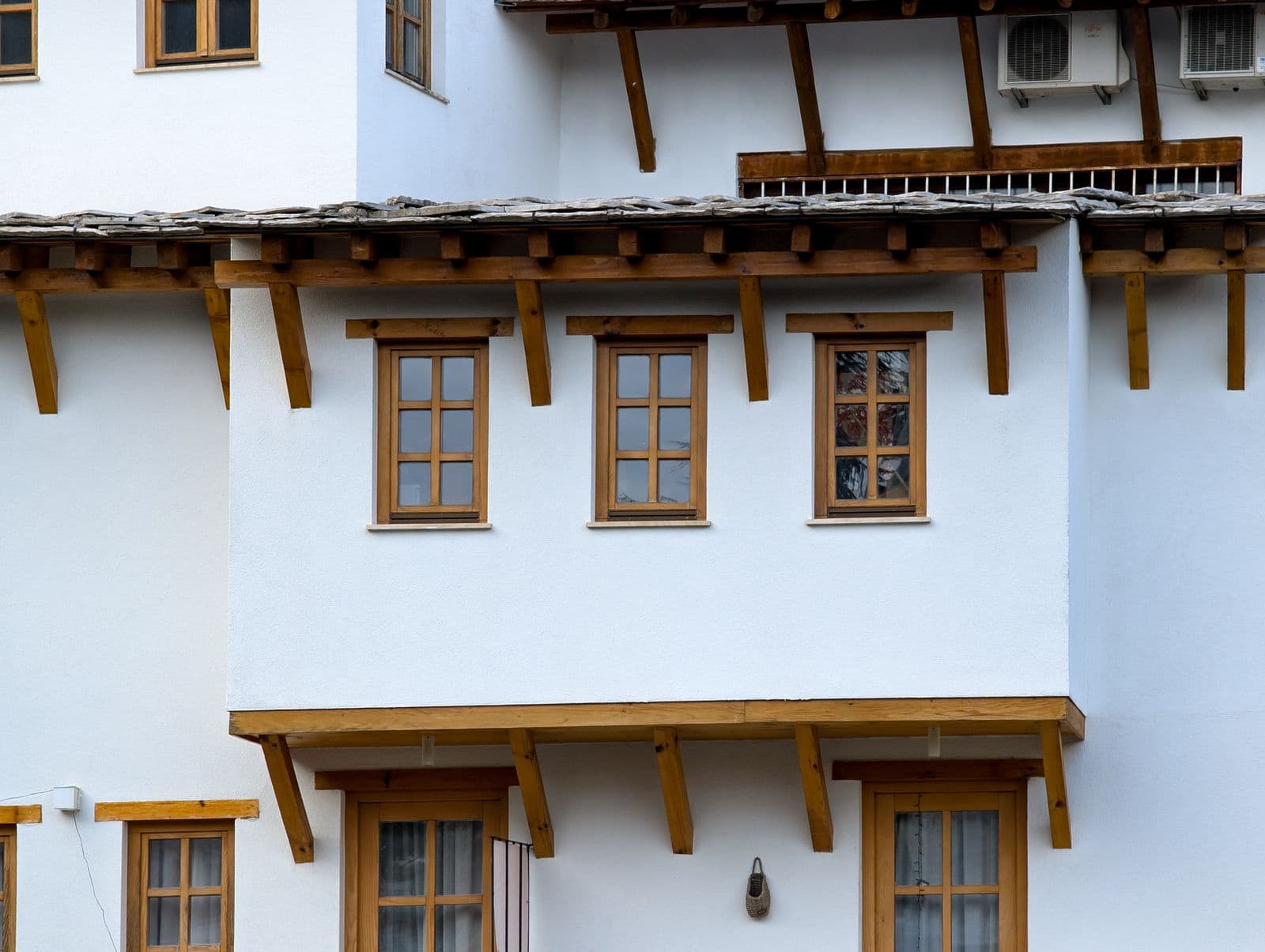 Close-up of traditional white house featuring wooden windows and roof elements.